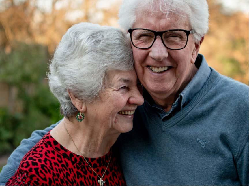 Image of elderly couple holding one another and smiling